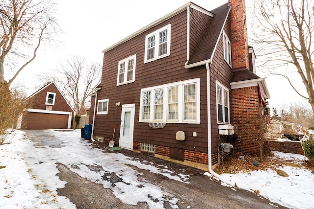 view of snowy exterior with a garage and an outdoor structure