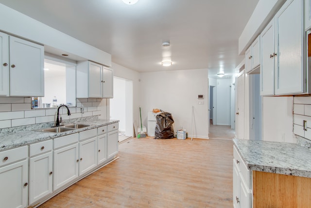 kitchen with white cabinetry, sink, backsplash, and light hardwood / wood-style floors