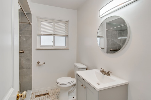 bathroom with a tile shower, vanity, tile patterned floors, and toilet