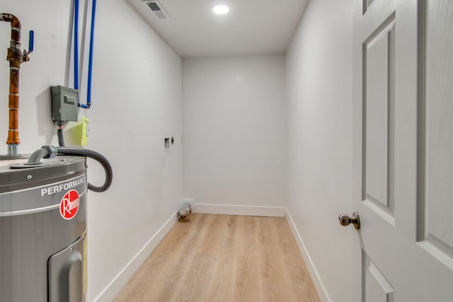 laundry area with hookup for an electric dryer, water heater, and light wood-type flooring