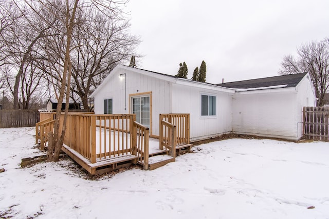 snow covered rear of property with a wooden deck