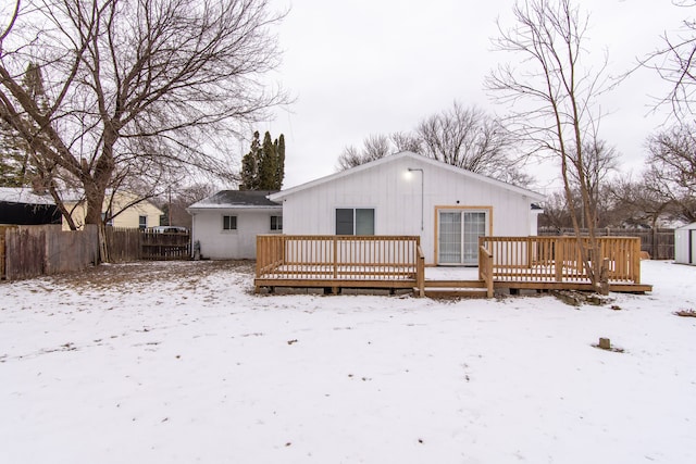 snow covered house with a storage unit and a deck