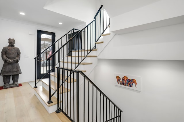 stairway featuring hardwood / wood-style floors and crown molding