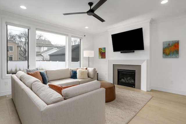 living room with ornamental molding, ceiling fan, and light hardwood / wood-style floors