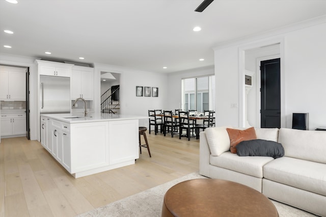 kitchen with white cabinetry, sink, light hardwood / wood-style flooring, and a breakfast bar