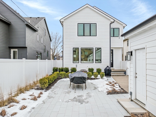 snow covered back of property with a patio area