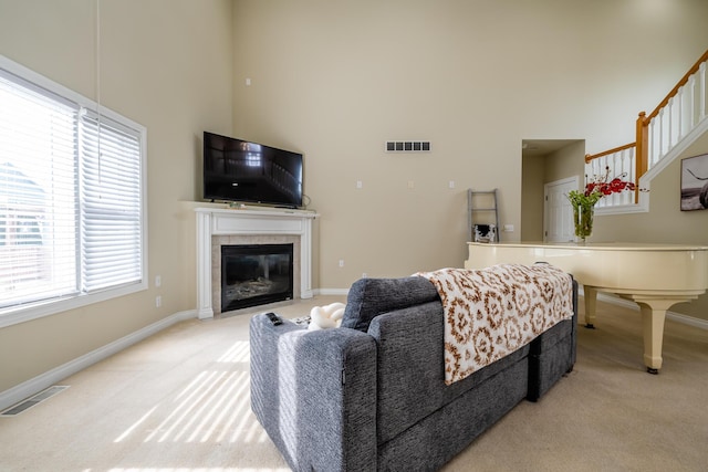 living room featuring a towering ceiling, light colored carpet, and a fireplace