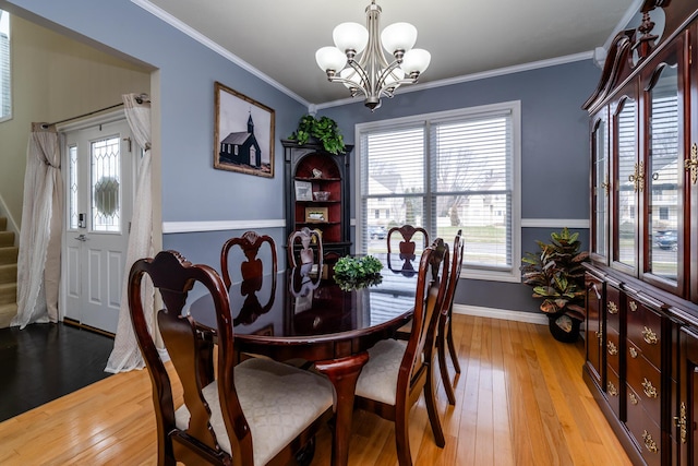 dining space with crown molding, plenty of natural light, an inviting chandelier, and light wood-type flooring