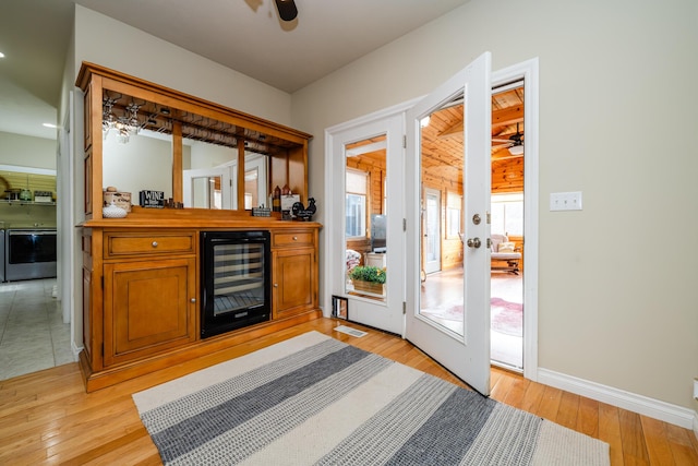 doorway to outside with bar area, wine cooler, ceiling fan, and light hardwood / wood-style floors