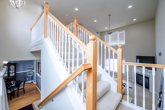 stairs with a high ceiling, hardwood / wood-style floors, and ceiling fan