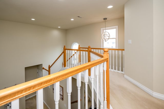 hallway featuring light colored carpet and a chandelier