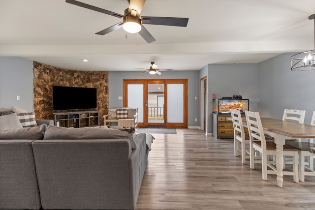 living room featuring ceiling fan with notable chandelier and light hardwood / wood-style floors