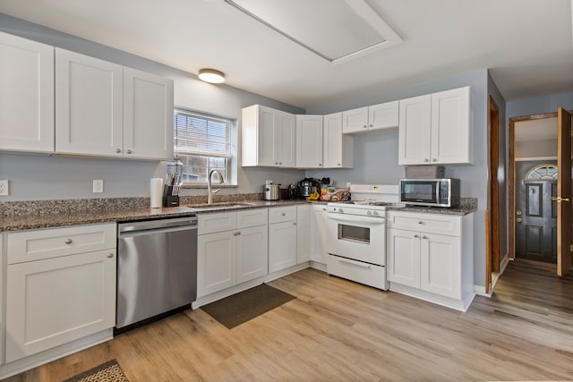 kitchen with appliances with stainless steel finishes, sink, dark stone countertops, and white cabinets