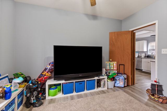 rec room featuring ceiling fan, sink, and light wood-type flooring