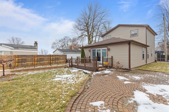 snow covered house with a yard, a patio area, and a deck