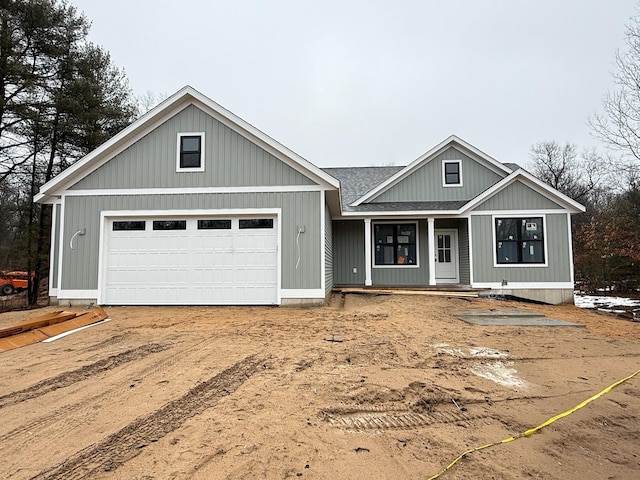 view of front of property with dirt driveway, a porch, roof with shingles, and an attached garage