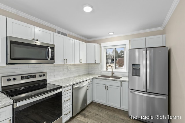 kitchen with stainless steel appliances, light stone countertops, sink, and white cabinets