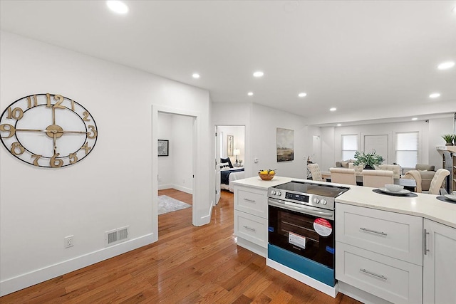 kitchen featuring white cabinetry, stainless steel range with electric stovetop, and hardwood / wood-style flooring