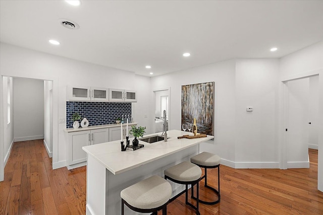 kitchen featuring sink, white cabinets, a kitchen bar, and light hardwood / wood-style floors