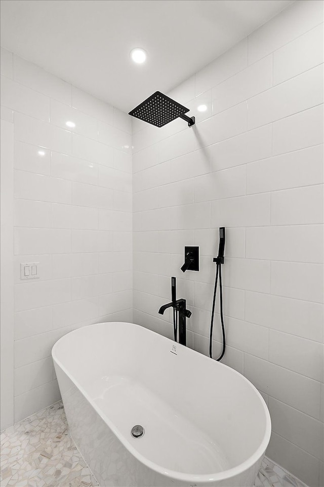 bathroom featuring a bath and tile walls