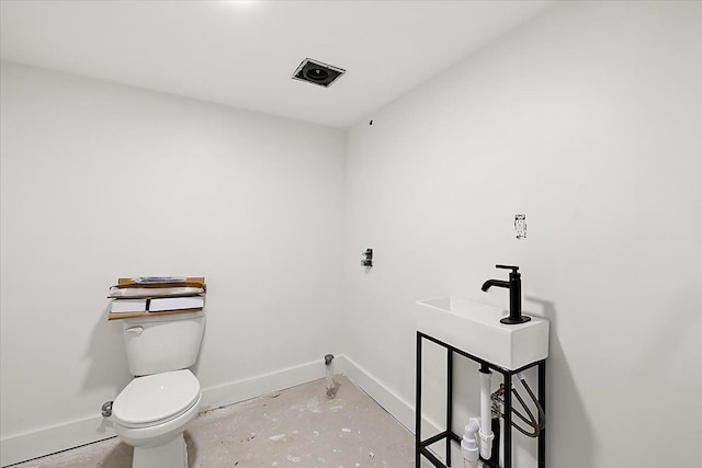 bathroom with concrete flooring and toilet