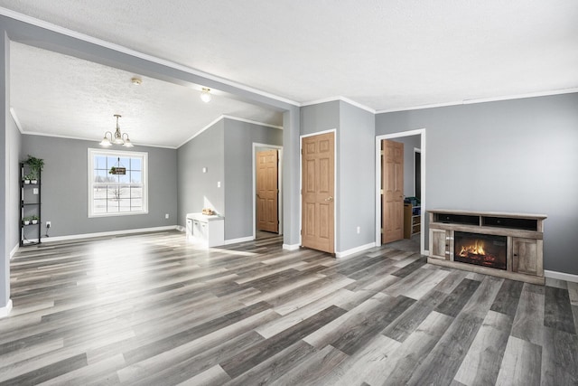 unfurnished living room with hardwood / wood-style flooring, crown molding, a textured ceiling, and a chandelier