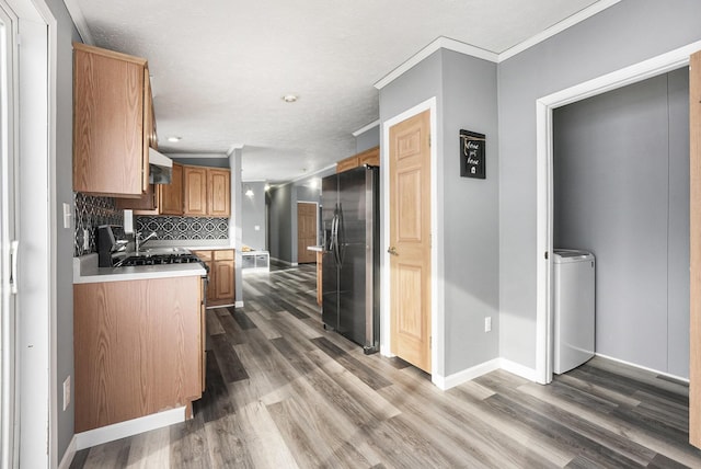 kitchen featuring washer / clothes dryer, dark wood-type flooring, stainless steel fridge, and decorative backsplash