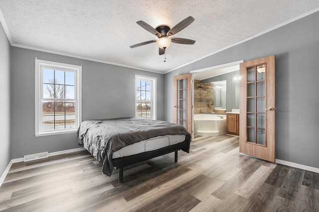 bedroom with connected bathroom, crown molding, a textured ceiling, ceiling fan, and hardwood / wood-style floors