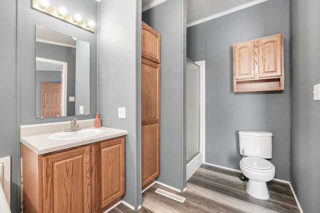 bathroom with walk in shower, toilet, wood-type flooring, ornamental molding, and vanity