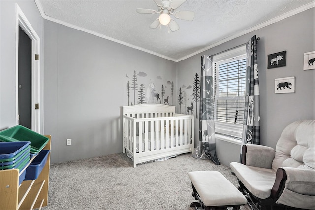 bedroom featuring carpet flooring, ornamental molding, ceiling fan, a crib, and a textured ceiling