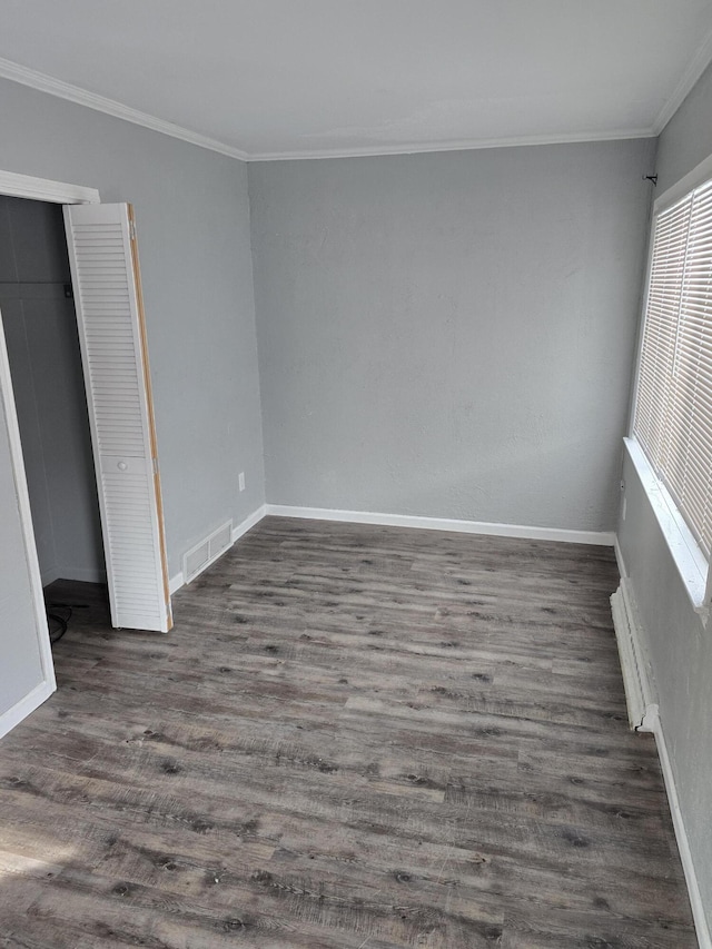 empty room with ornamental molding and dark hardwood / wood-style flooring