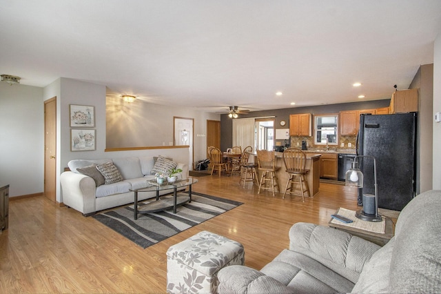 living room with ceiling fan, sink, and light hardwood / wood-style floors