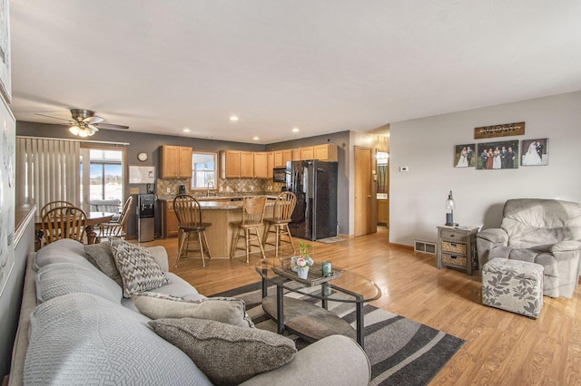 living room featuring ceiling fan, sink, and light wood-type flooring