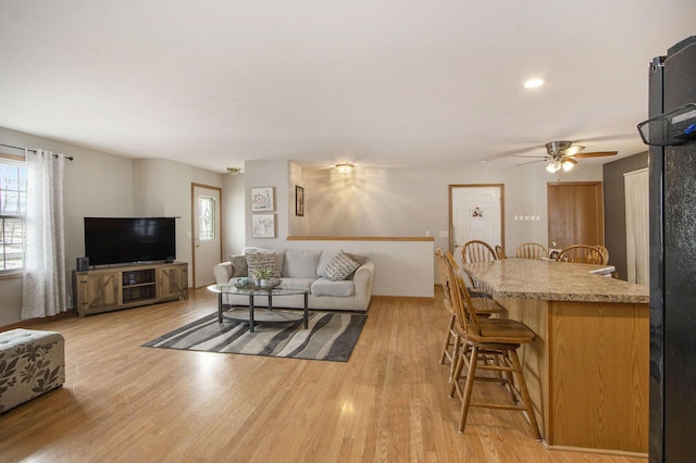 living room featuring light hardwood / wood-style flooring and ceiling fan