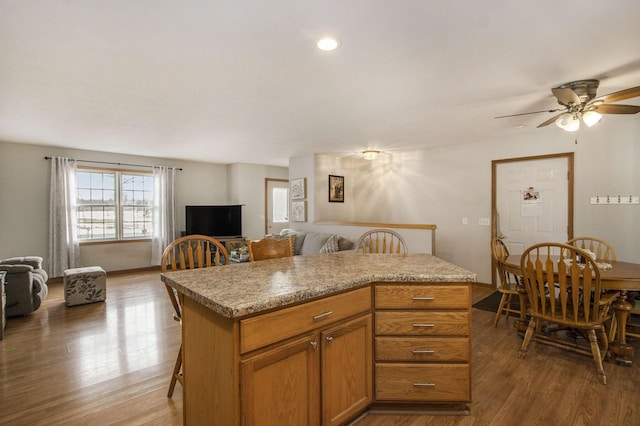 kitchen featuring ceiling fan, dark hardwood / wood-style flooring, and a center island