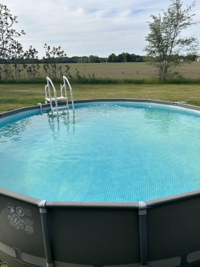 view of pool featuring a yard and a rural view