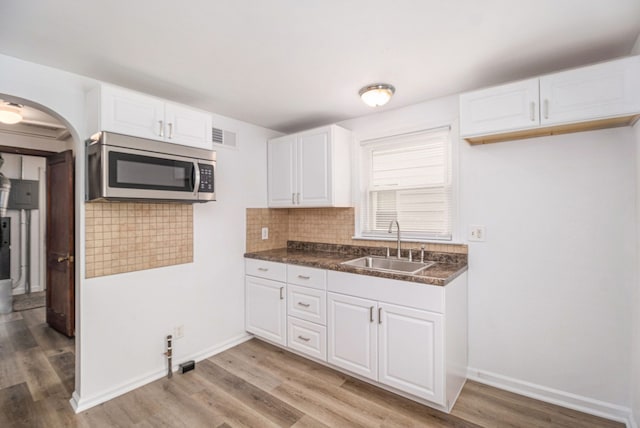 kitchen with sink, white cabinets, light hardwood / wood-style floors, and decorative backsplash