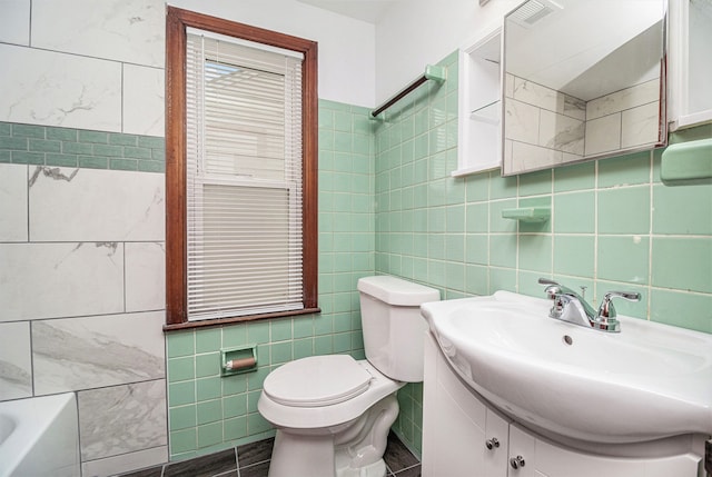 bathroom featuring vanity, toilet, tile walls, and a washtub