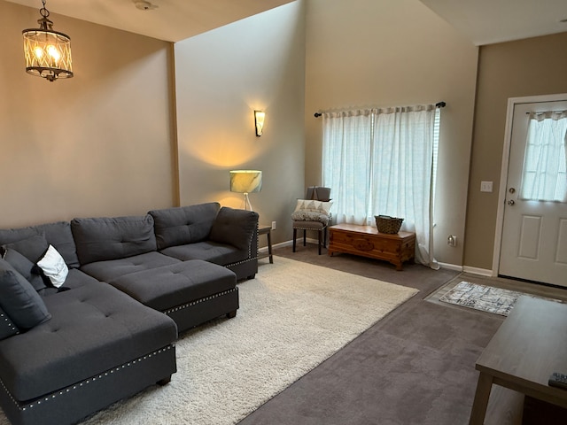 living room featuring high vaulted ceiling, a chandelier, and dark carpet