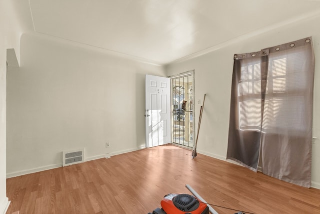 unfurnished room featuring baseboards, visible vents, and wood finished floors