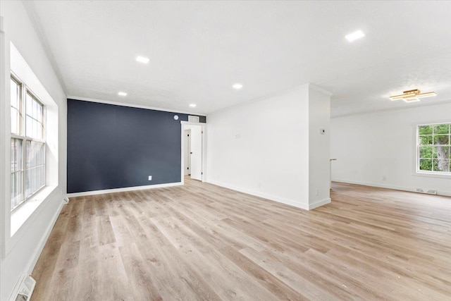 spare room with ornamental molding and light hardwood / wood-style floors