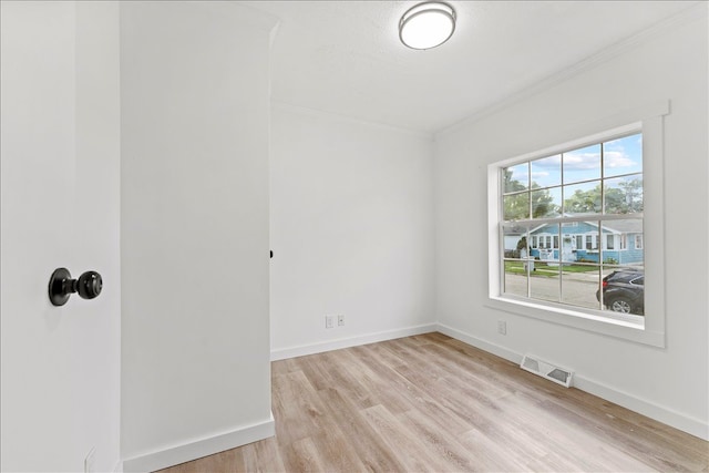 spare room featuring ornamental molding and light wood-type flooring