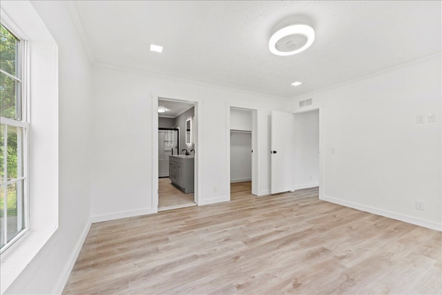 unfurnished bedroom featuring ornamental molding, multiple windows, and light wood-type flooring