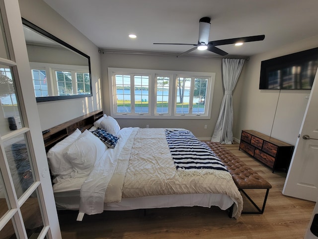 bedroom with hardwood / wood-style flooring, ceiling fan, and multiple windows