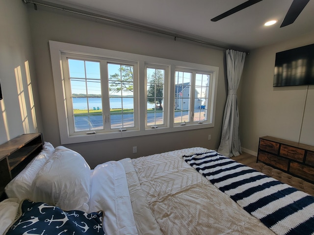 bedroom with ceiling fan and a water view