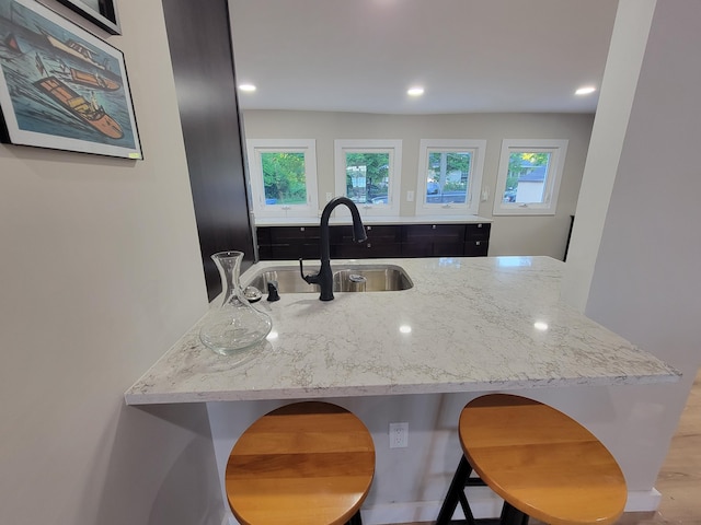 kitchen with sink, light stone countertops, and a kitchen bar