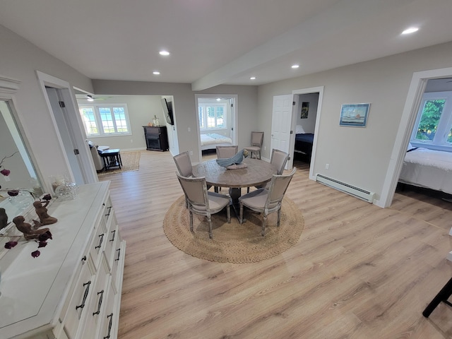 dining space featuring a baseboard heating unit, light hardwood / wood-style floors, and a healthy amount of sunlight