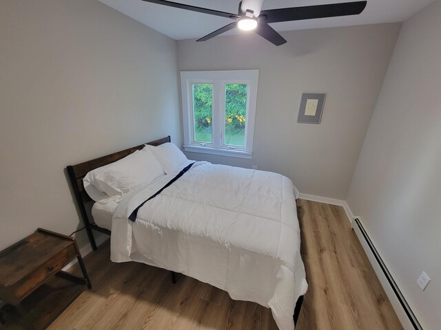 bedroom with baseboard heating, ceiling fan, and wood-type flooring