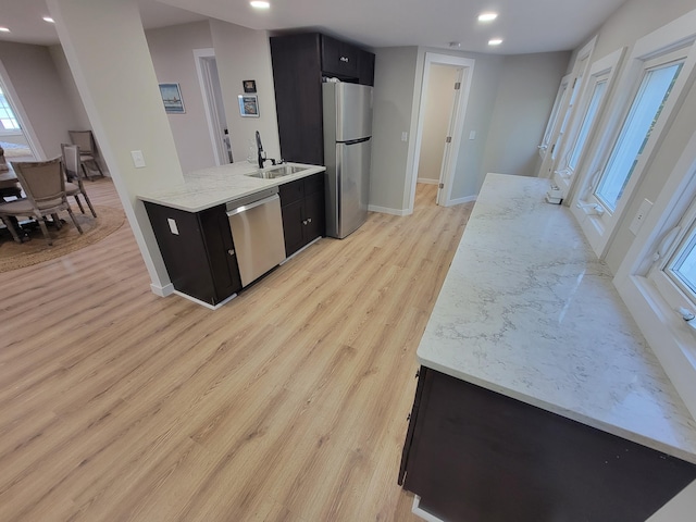 kitchen featuring light stone counters, appliances with stainless steel finishes, sink, and light hardwood / wood-style flooring