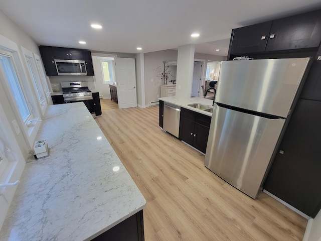 kitchen featuring appliances with stainless steel finishes, sink, light stone counters, and light wood-type flooring